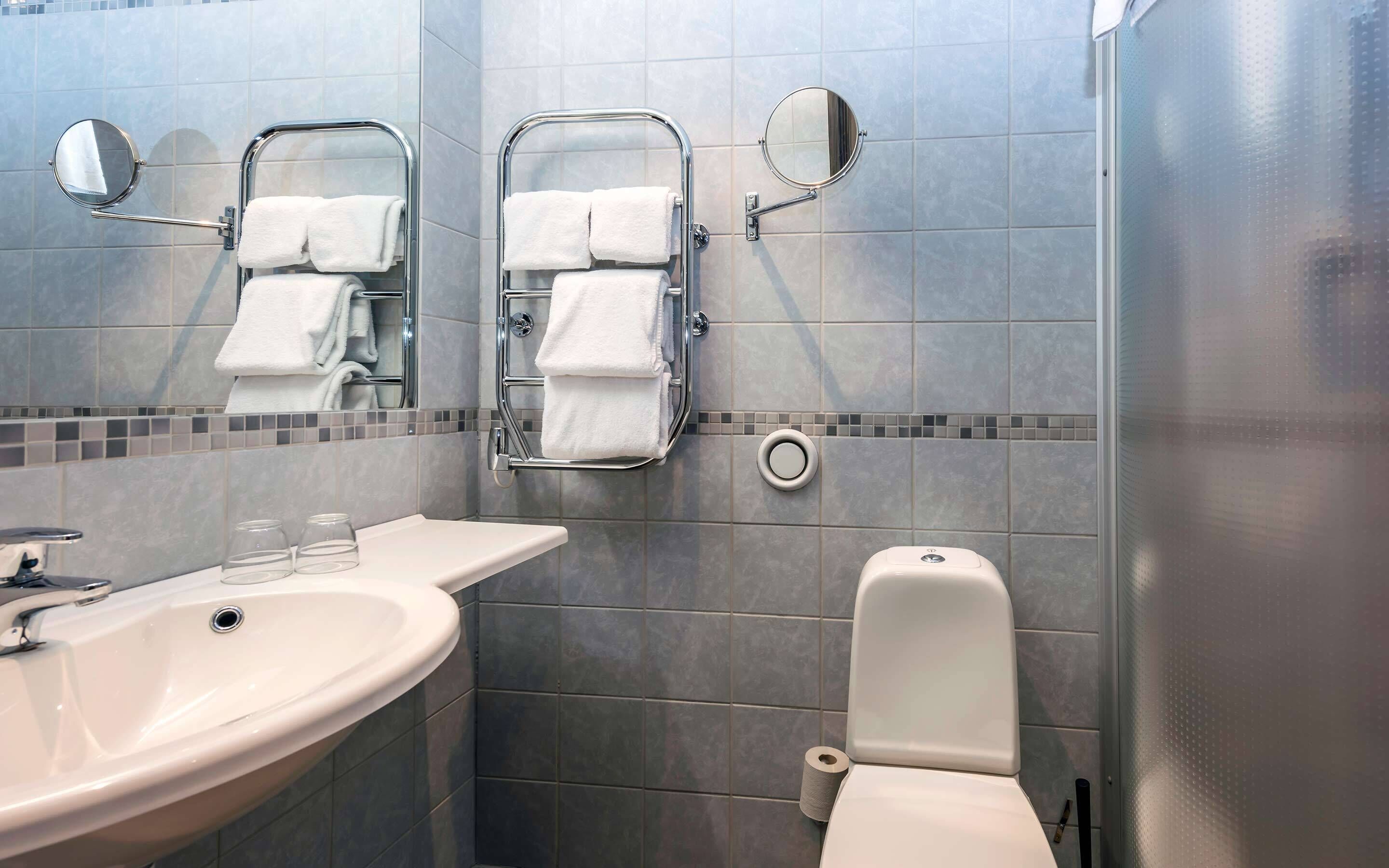 Un baño moderno con lavamanos, espejo, toallero y retrete.