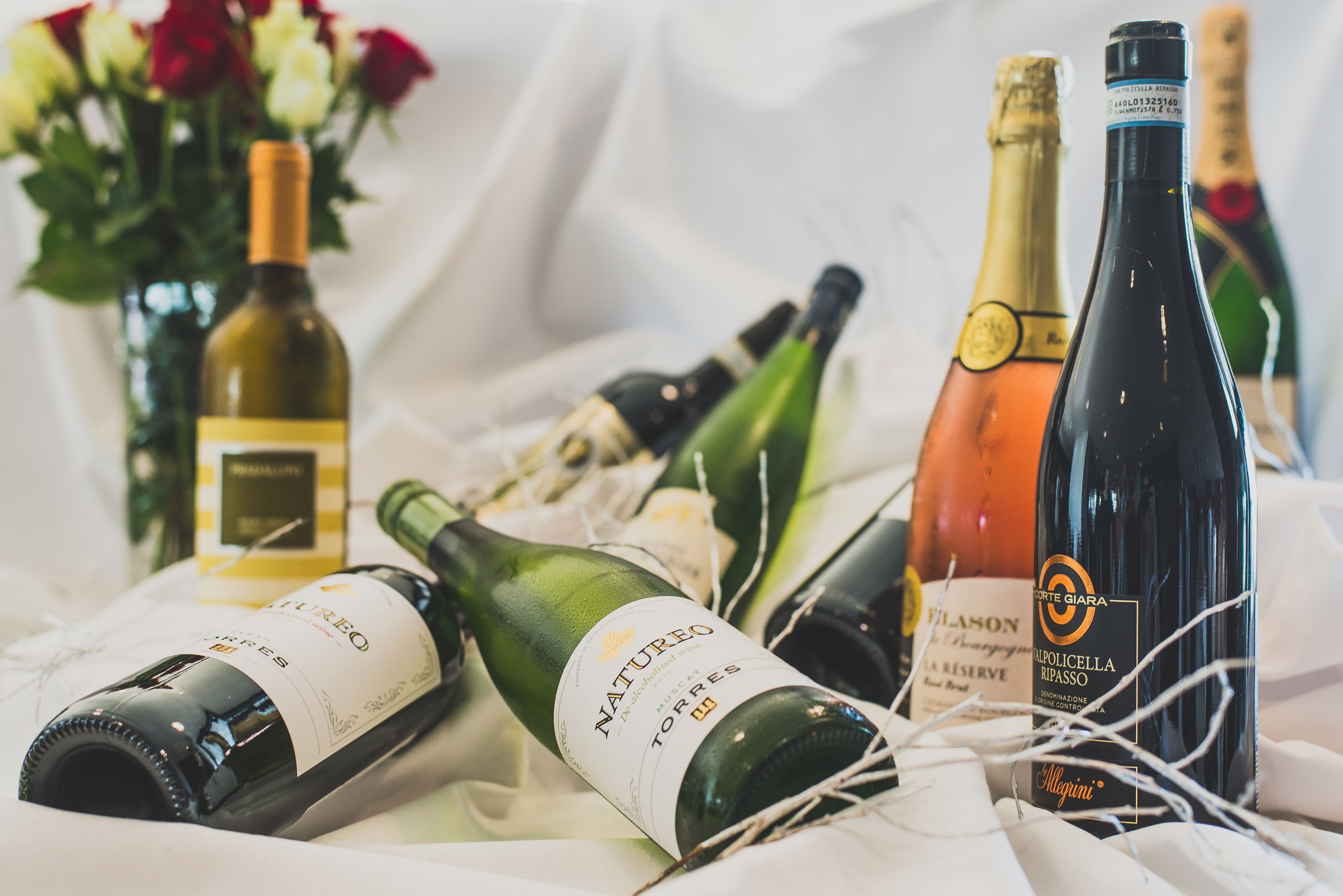 A variety of wine bottles on a table with a white cloth.