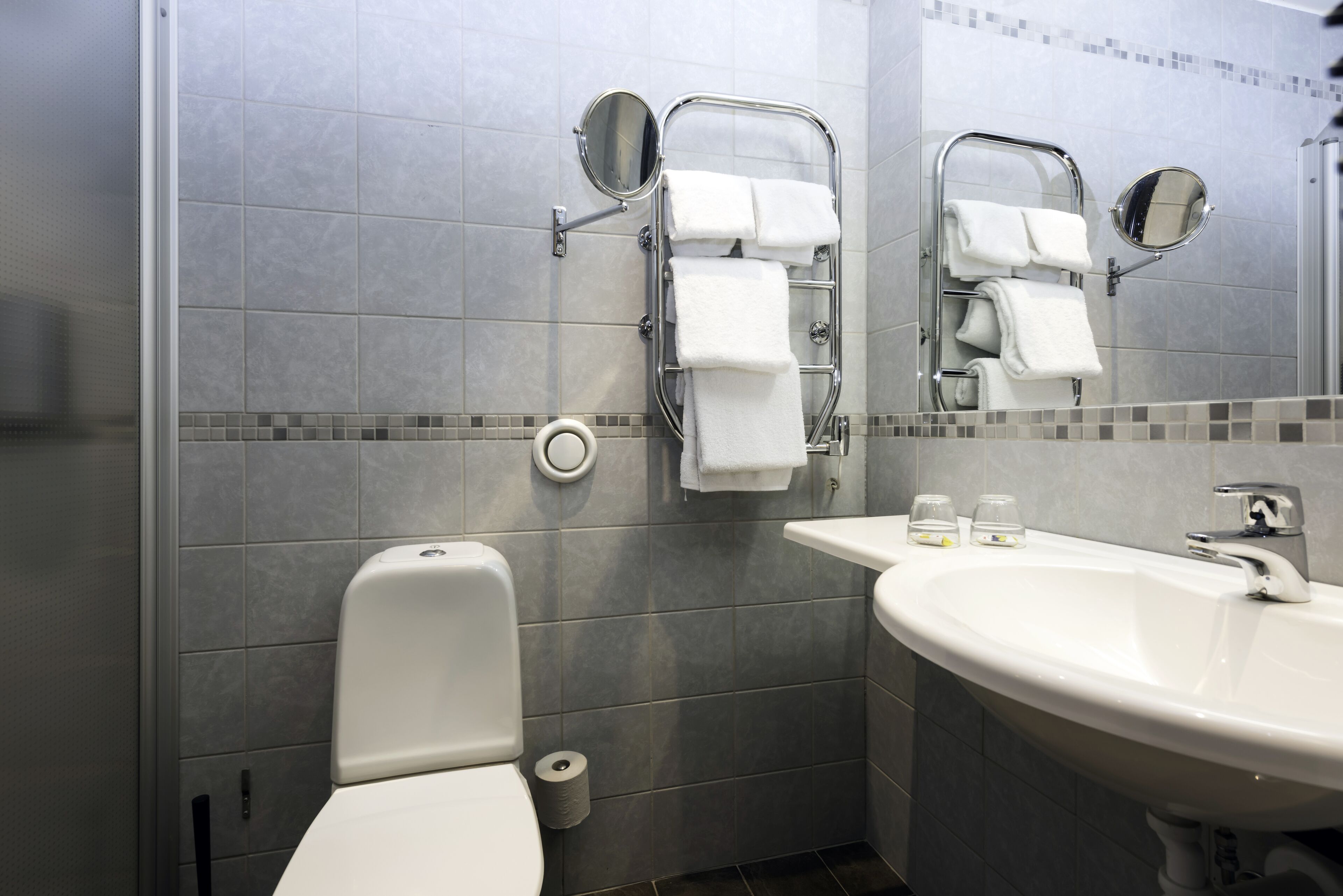 A modern bathroom with a toilet, a sink, and two towel racks with mirrors.