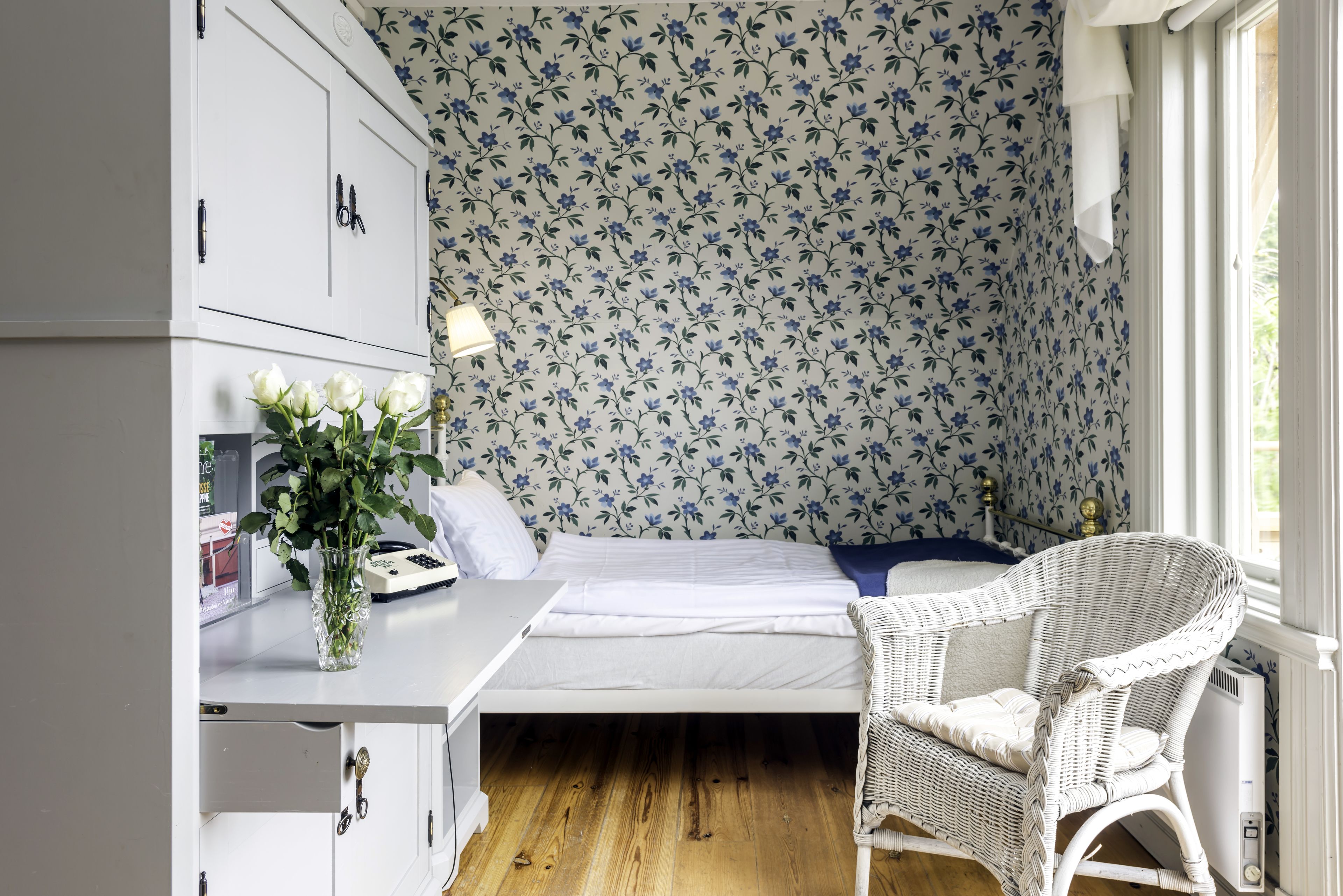 Una habitación pequeña con cama, escritorio, silla y radiador.
