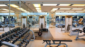 Un gimnasio con diversos equipos de ejercicio, espejos y un interior limpio y bien iluminado.