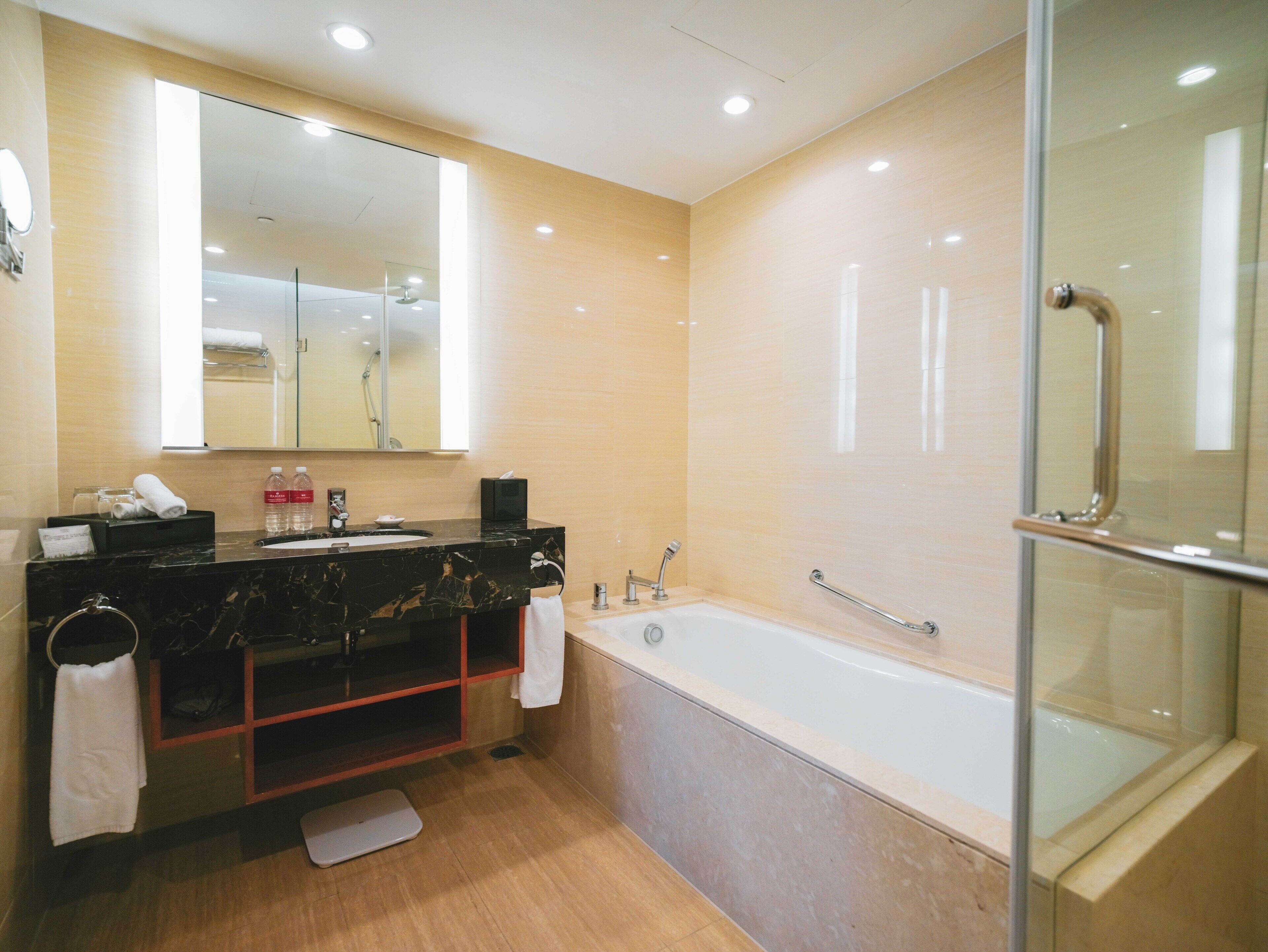 A modern bathroom with a large mirror, a bathtub, and a shower area.
