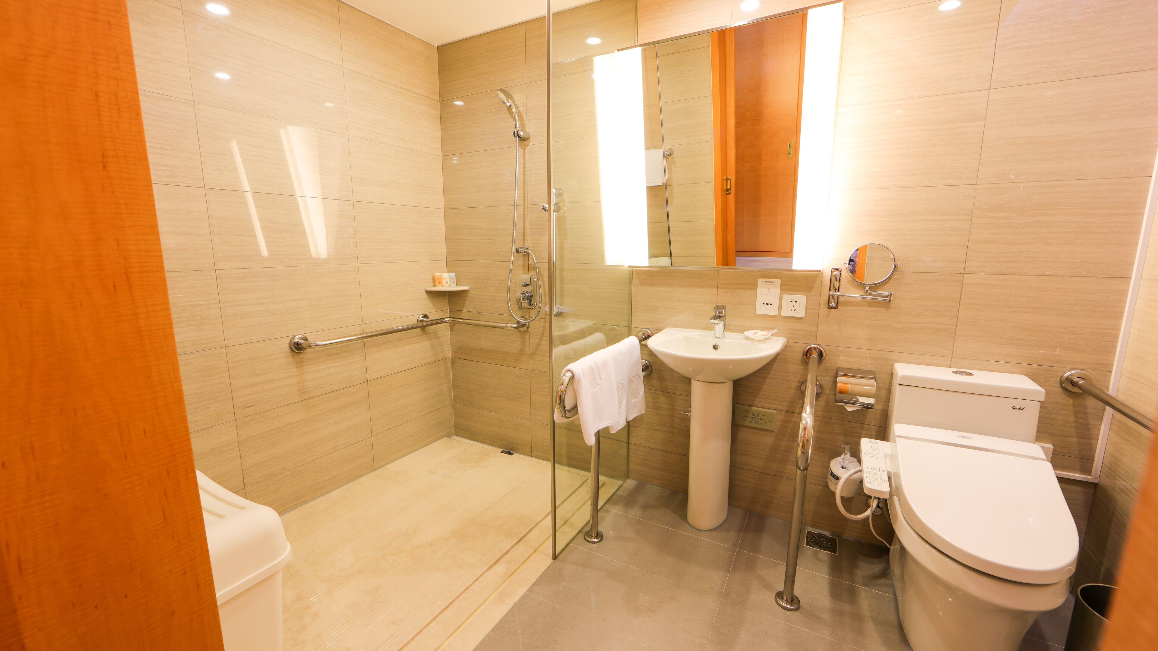 A modern bathroom with a glass-enclosed shower, a pedestal sink, a toilet, and a vanity with a mirror.