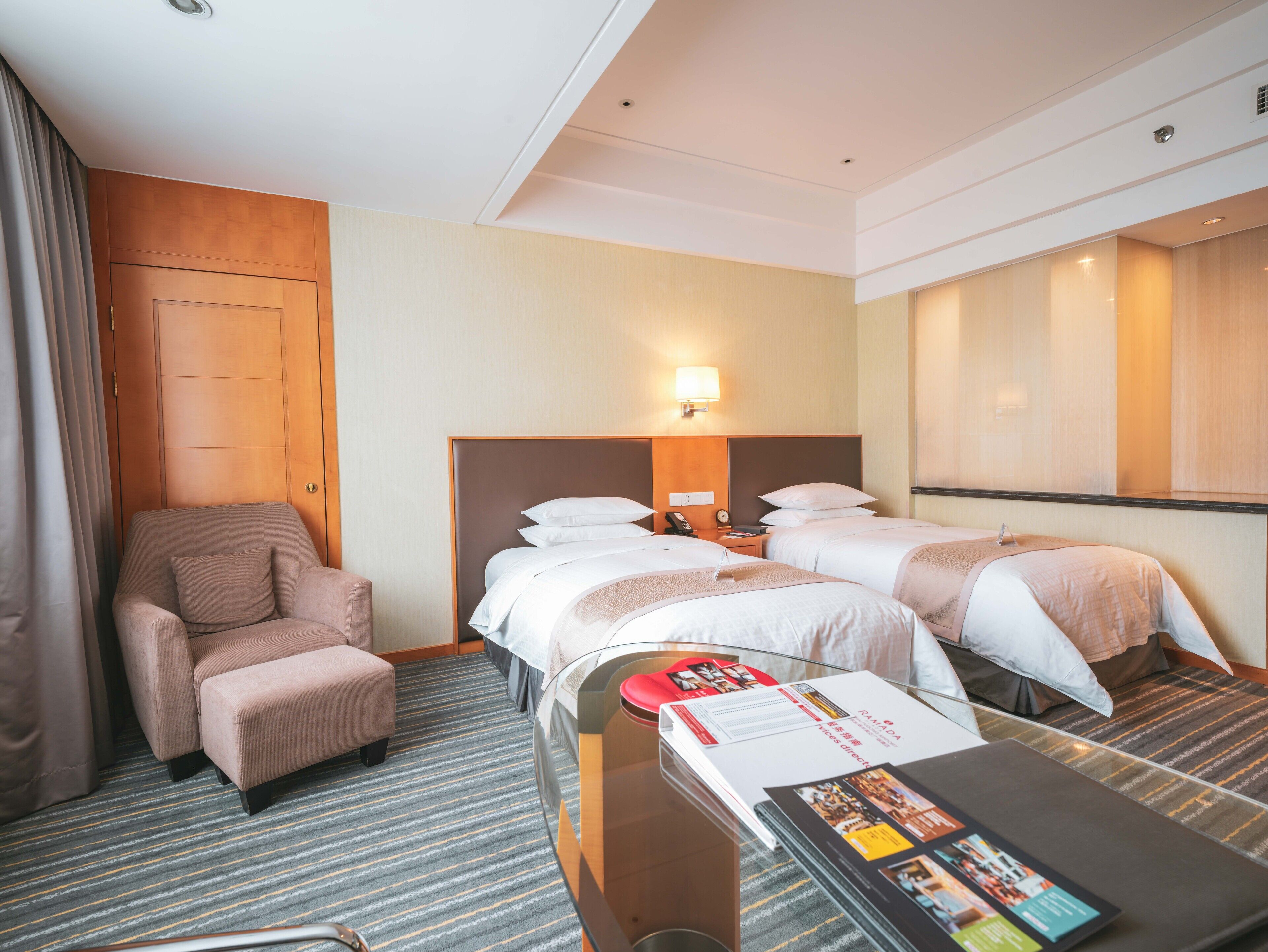 A hotel room with two beds, a sofa, a desk, and a mirror.