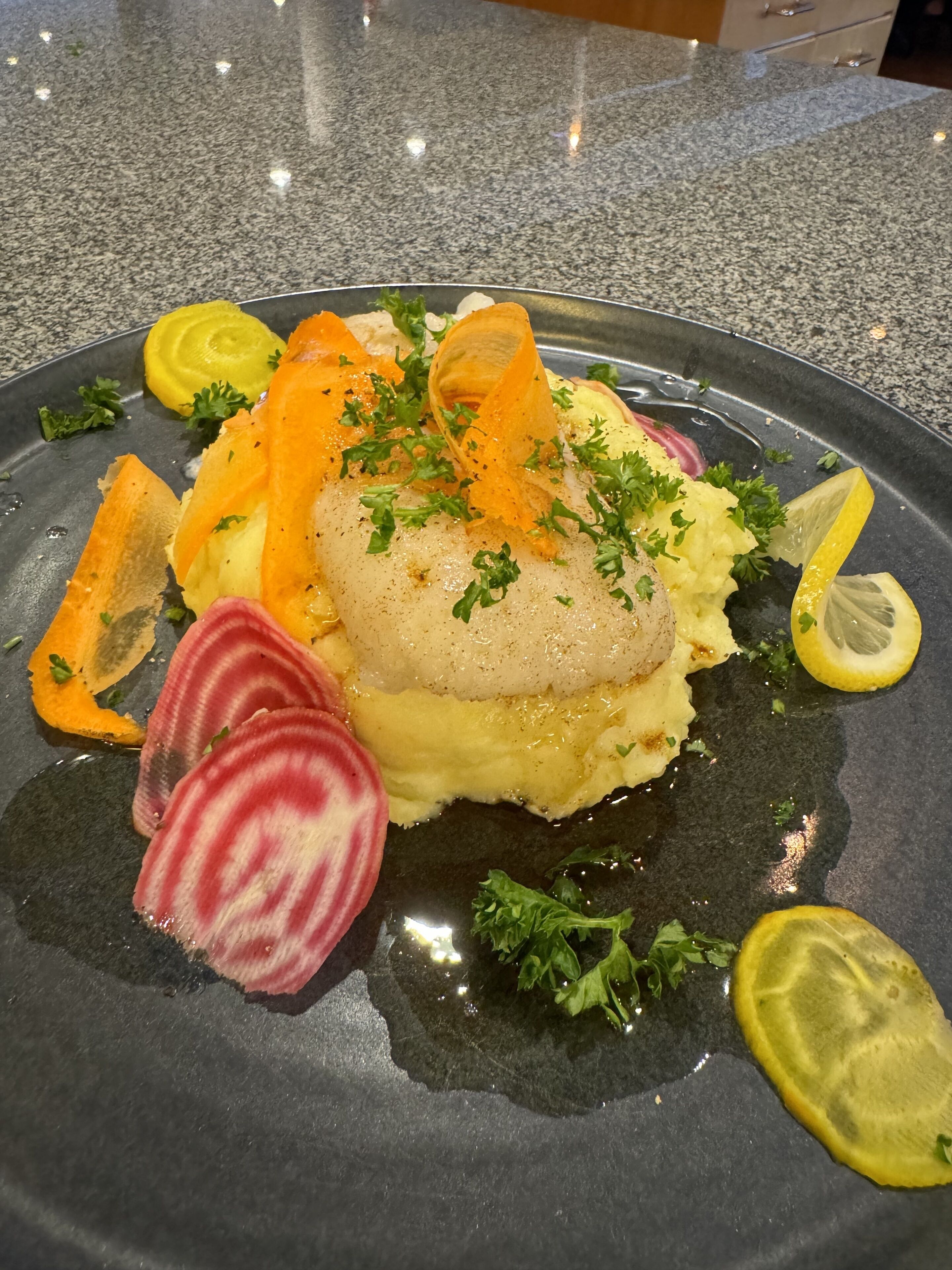 Un plato de comida con un filete de pescado, puré de papas y guarniciones.