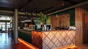 A modern reception area with a wooden counter, a potted plant, and a green wall.