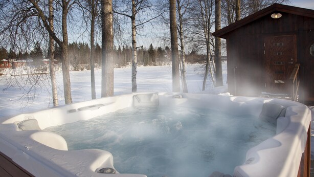 A hot tub surrounded by snow and trees.