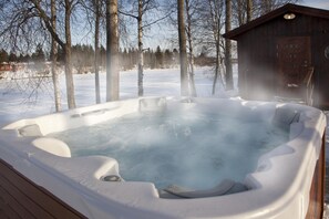 Un jacuzzi rodeado de nieve y árboles.