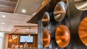 Una zona de recepción con un mostrador de madera, una pantalla grande mostrando una presentación y una pared con apliques de color cobre.