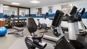 Et fitnessrum med træningsudstyr, håndvægte og en blå træningsbold.