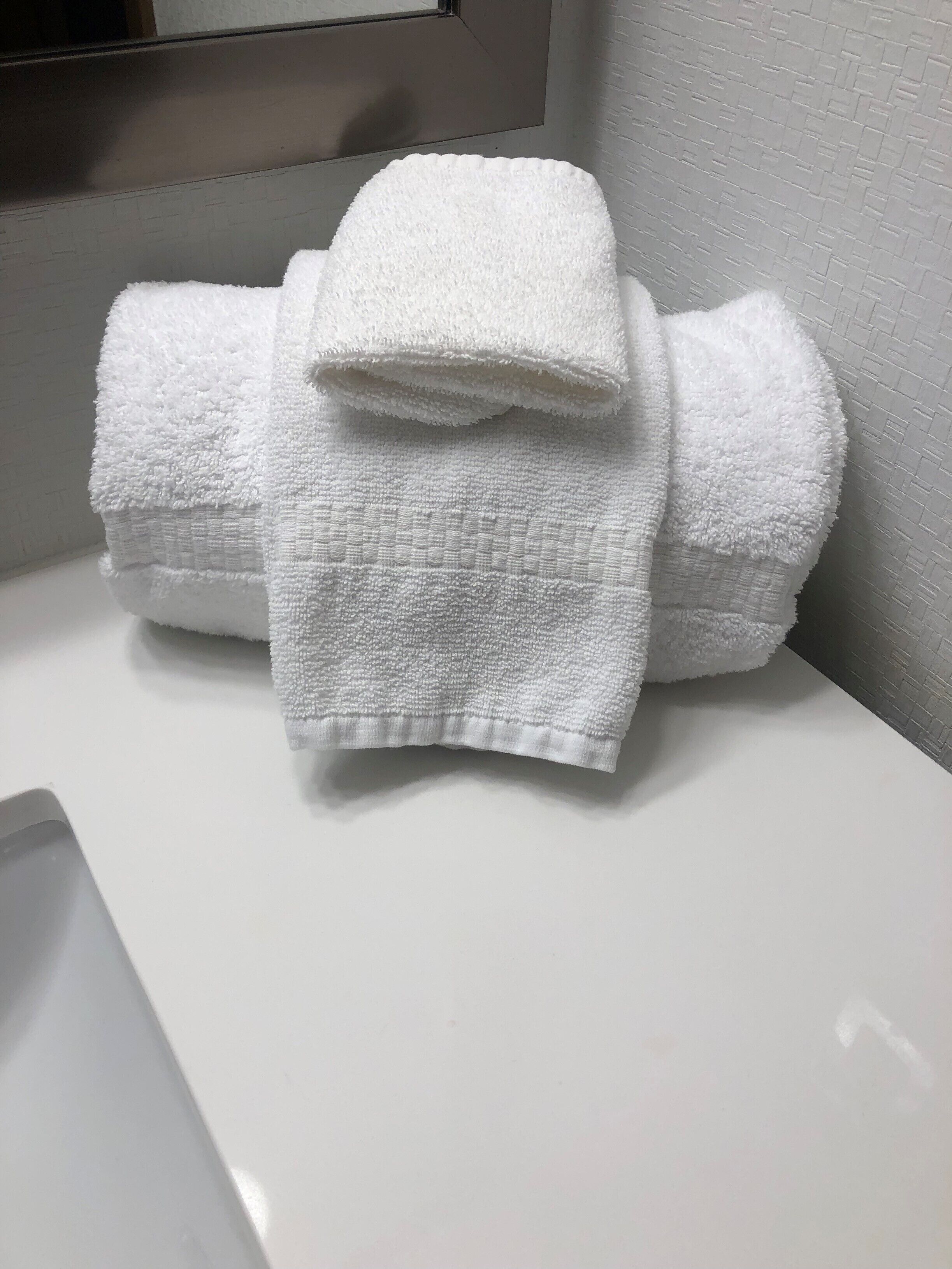 A white bathroom sink with a white towel folded on top.