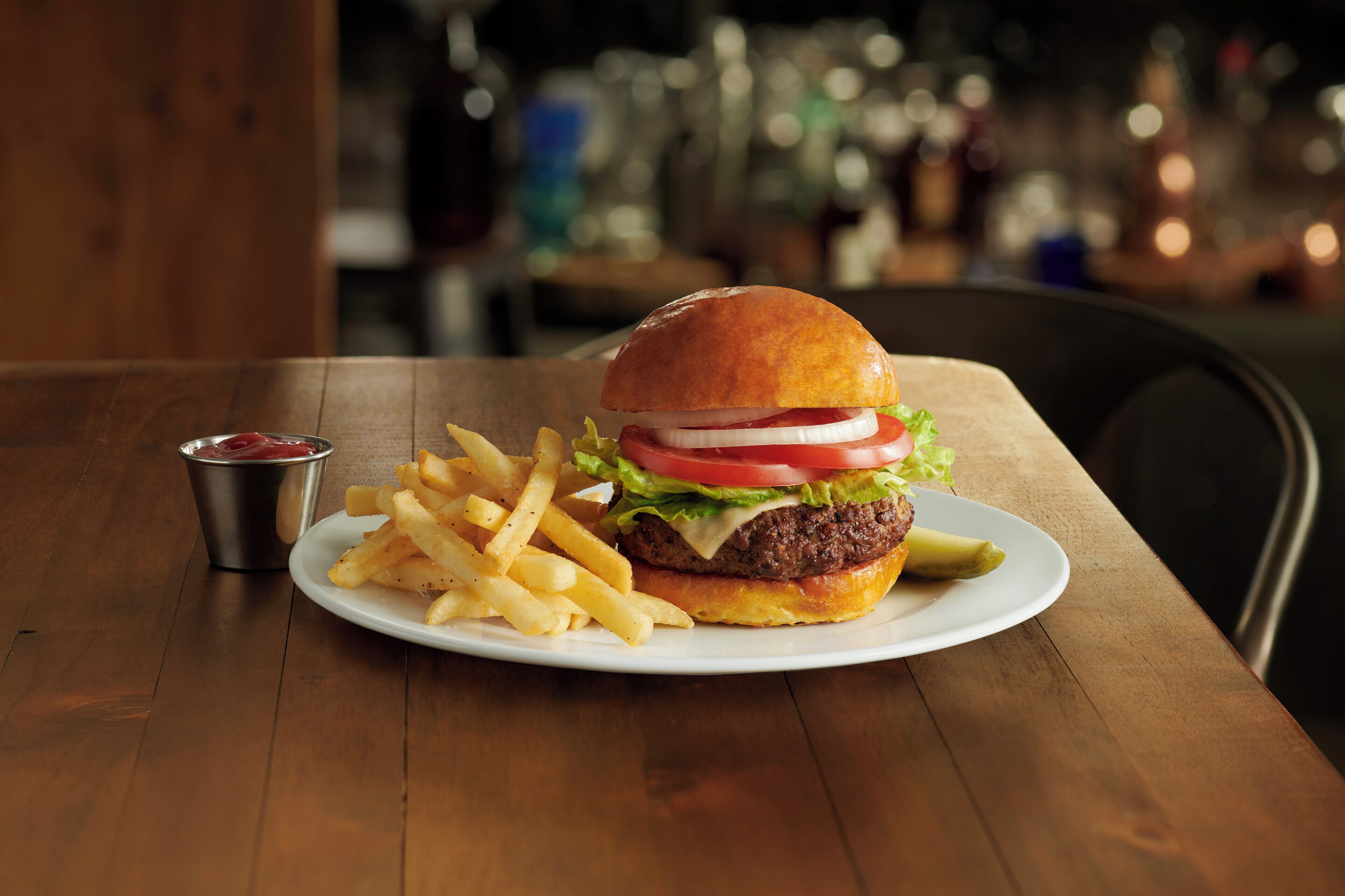 A burger with fries and ketchup on a wooden table.