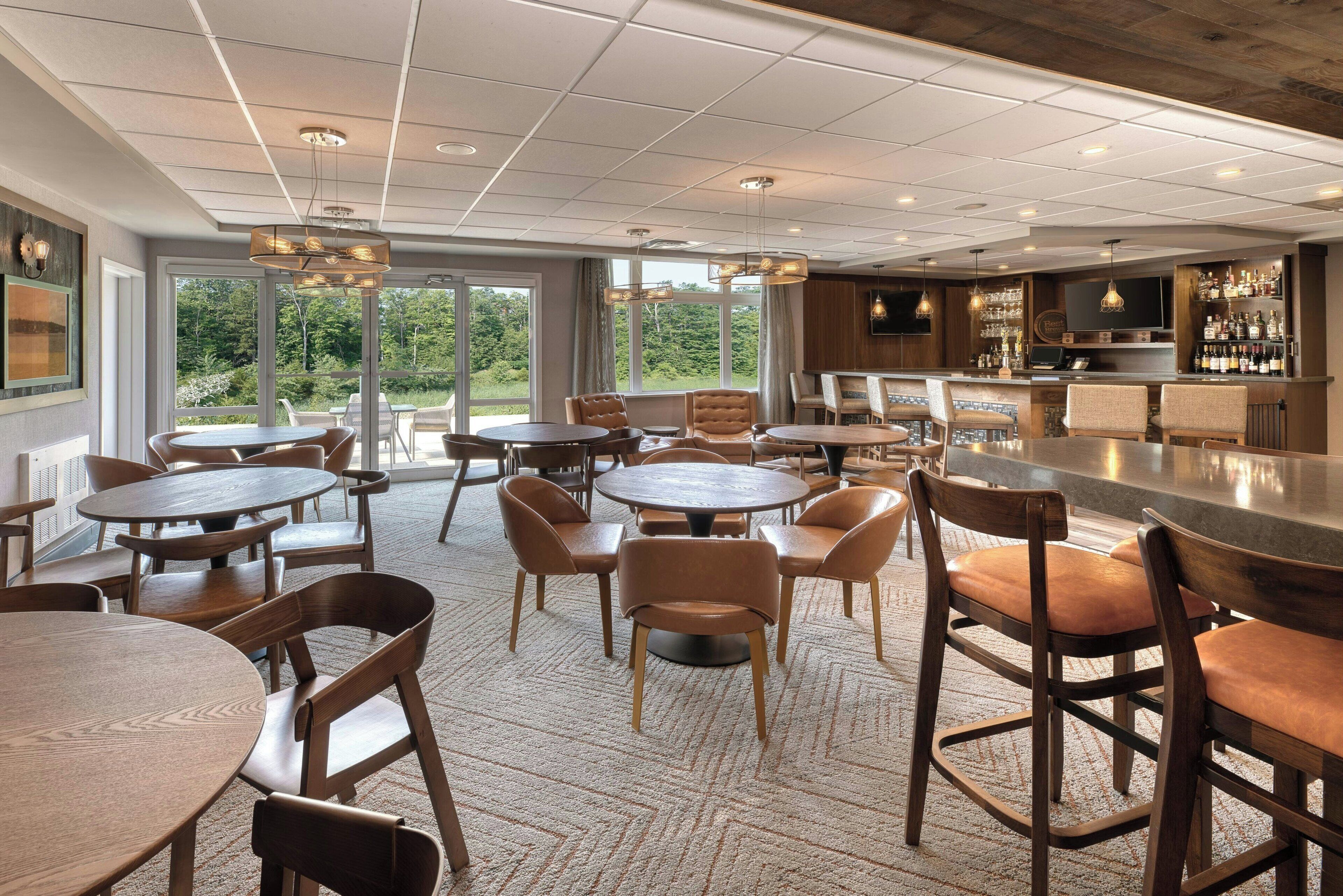 A bar area with round tables and chairs, a bar counter, and a television screen.