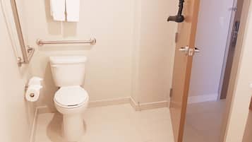 A bathroom with a toilet, a towel rack, and a shower area.