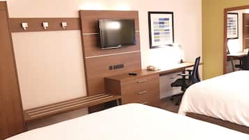 Habitación de hotel con cama, escritorio y silla, televisión e imagen enmarcada en la pared.