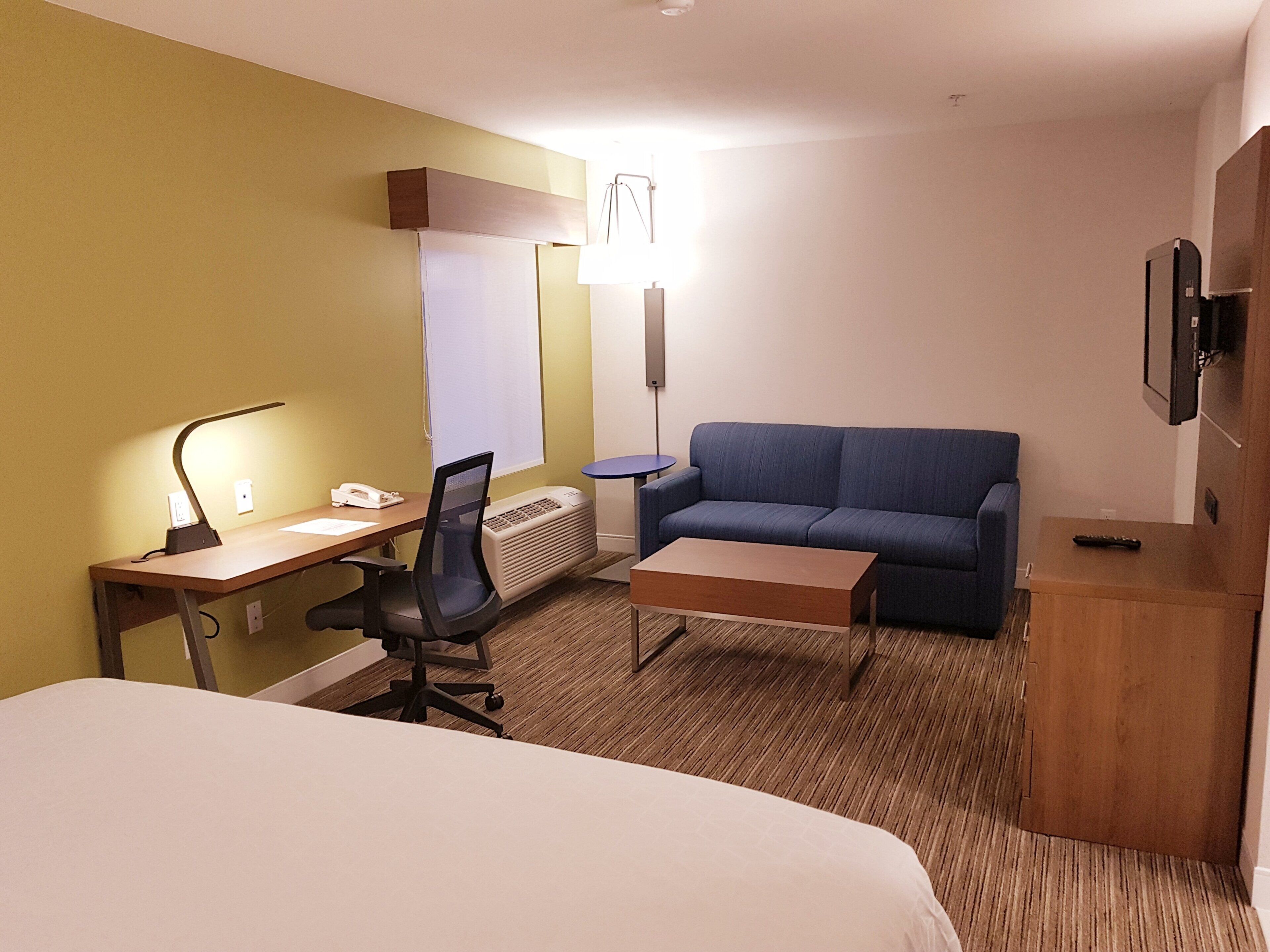 Une chambre d’hôtel équipée d’un lit, d’un bureau, d’une chaise, d’un canapé et d’une télévision.
