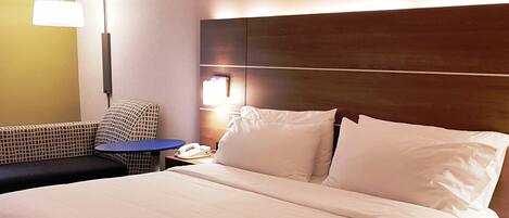 Una habitación de hotel con cama, sofá, mesita, teléfono y lámpara.