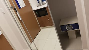 Un pasillo estrecho con un microondas, un mueble pequeño y un dispositivo azul en una estantería.