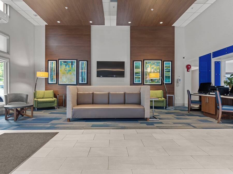 A lobby with a sofa, chairs, a desk with computers, and artwork on the walls.