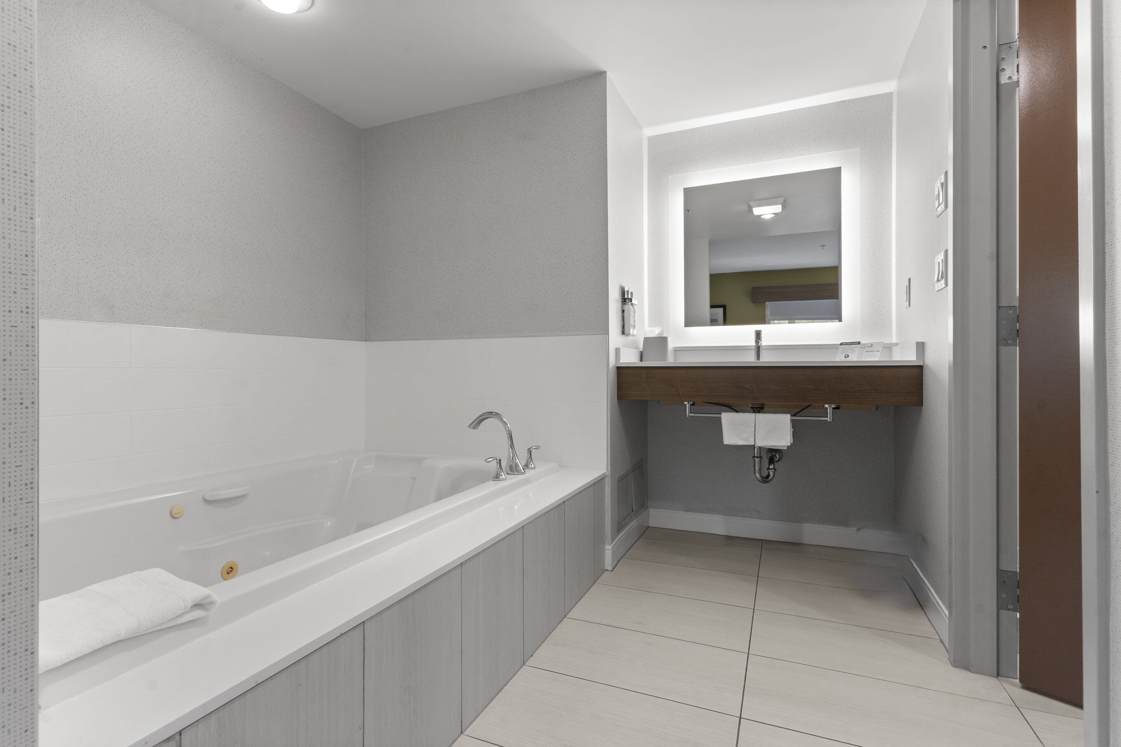 Un bagno moderno con una vasca da bagno grande, un mobile lavabo con specchio e un water.