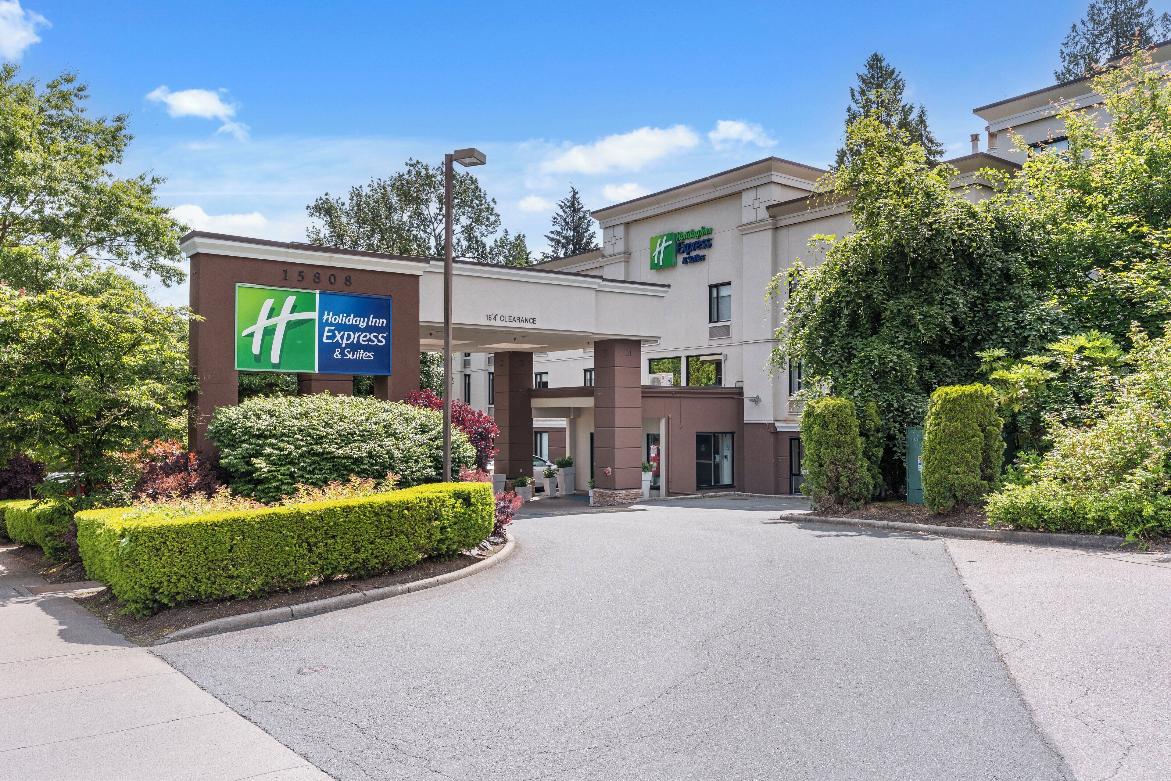 A Holiday Inn Express & Suites building with a clear entrance, well-maintained landscaping, and a visible parking area.