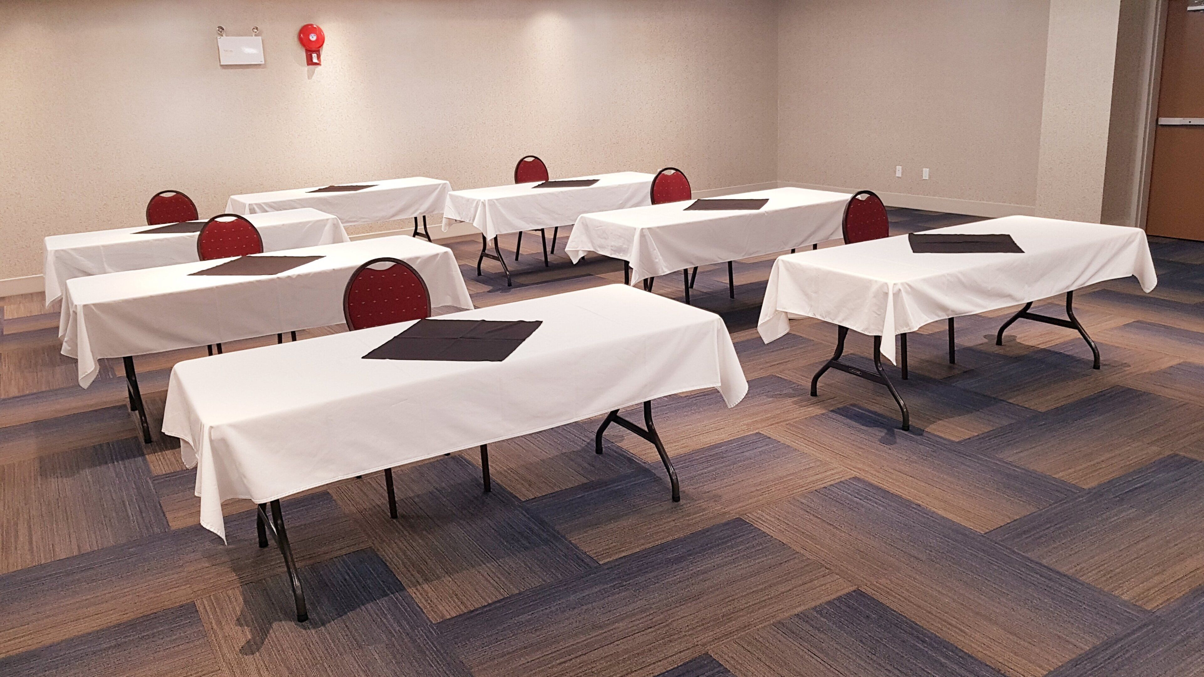 Un salón de conferencias con varias mesas y sillas dispuestas en filas.