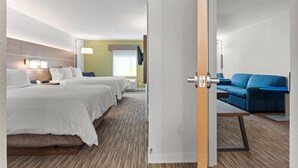 Habitació d'hotel amb dos llits, un sofà, escriptori i un bany visible a través d'una porta oberta.