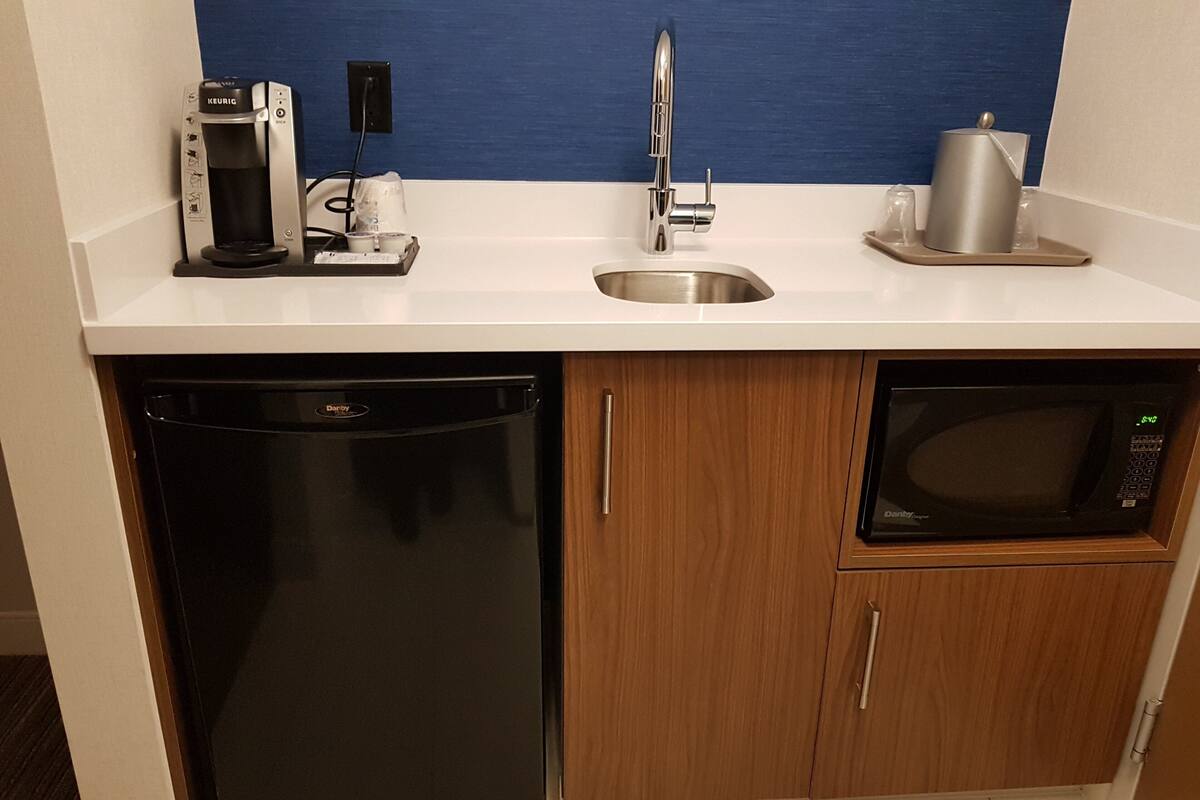 A compact kitchen with a dishwasher, a microwave, and a coffee maker.