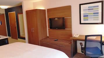 Habitación de hotel con una cama, un escritorio con teléfono, televisión y armario.