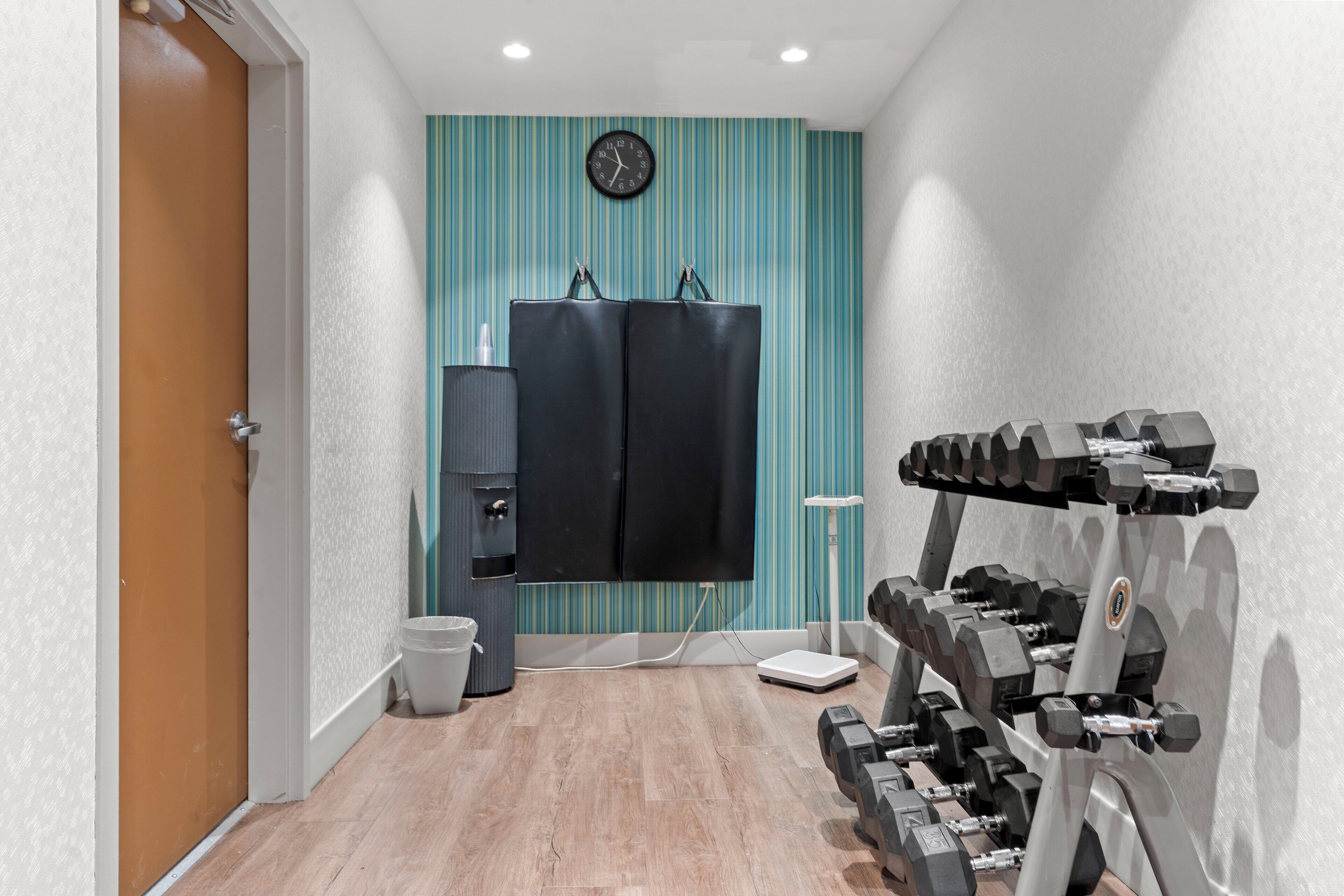 Un gimnasio con un espejo grande, una balanza y un reloj en la pared.