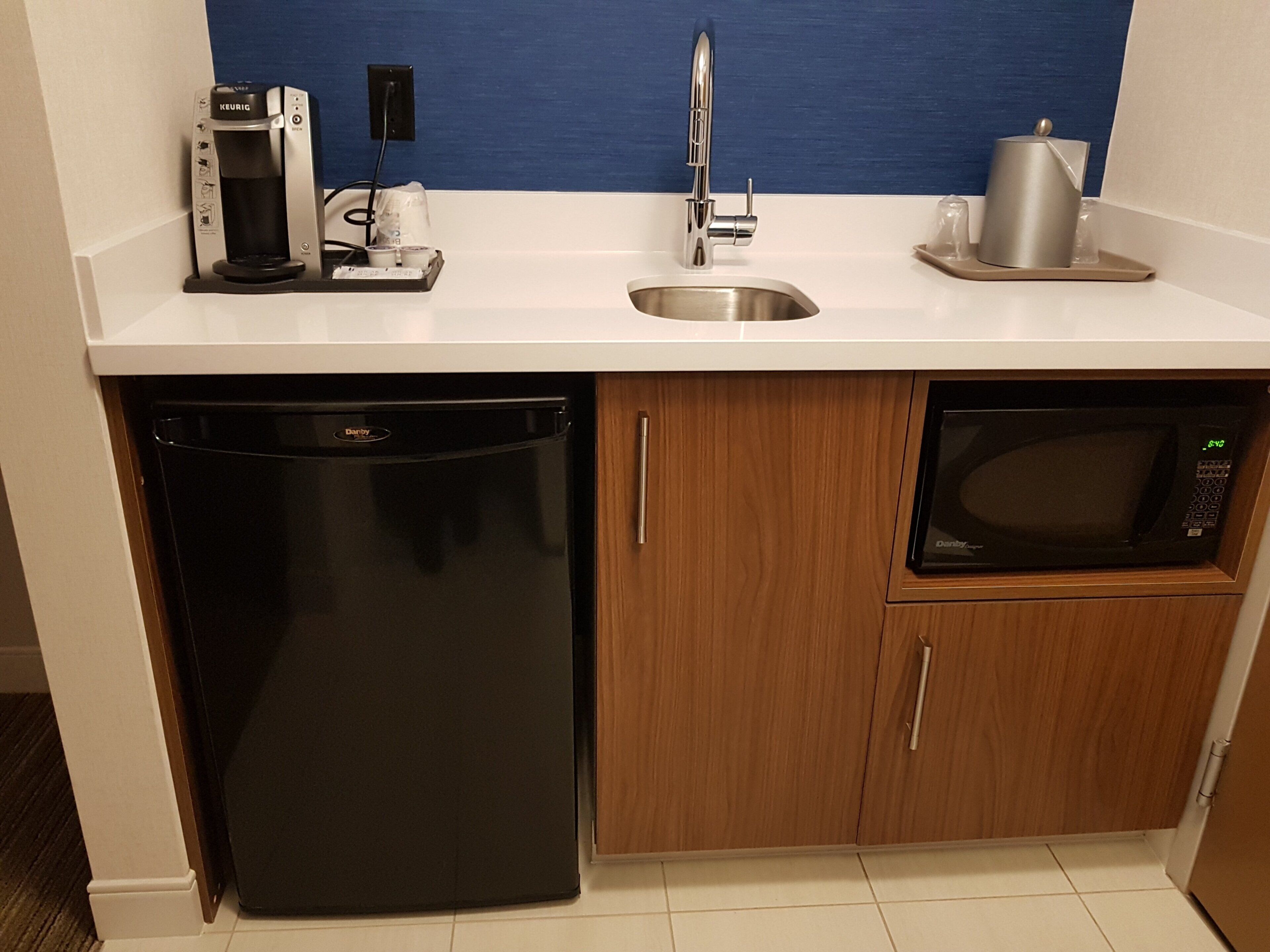 Cocina compacta equipada con lavavajillas, microondas y cafetera.