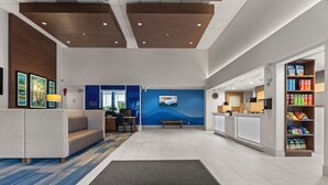 Un vestíbul d'hotel amb una recepció, zona de seients i una barra de mossegafuites.