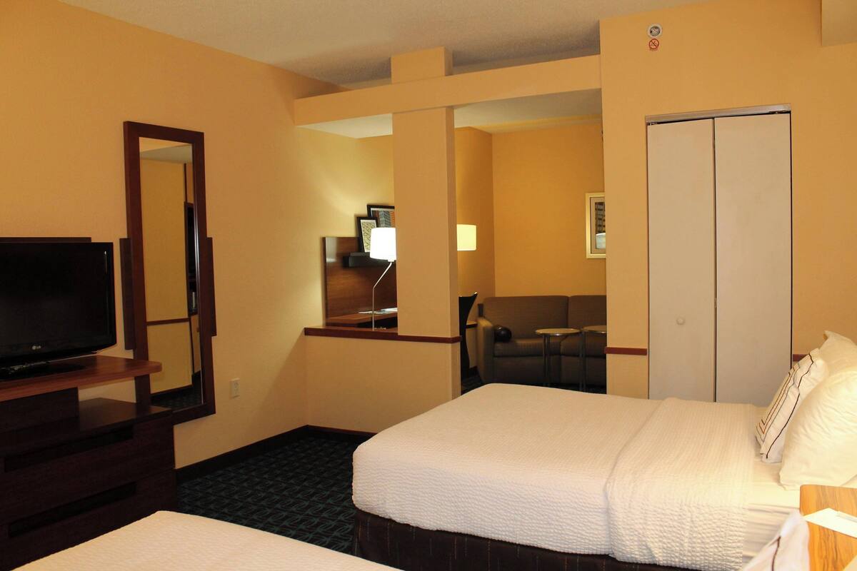 A hotel room with a bed, a TV, a mirror, a desk, and a wardrobe.