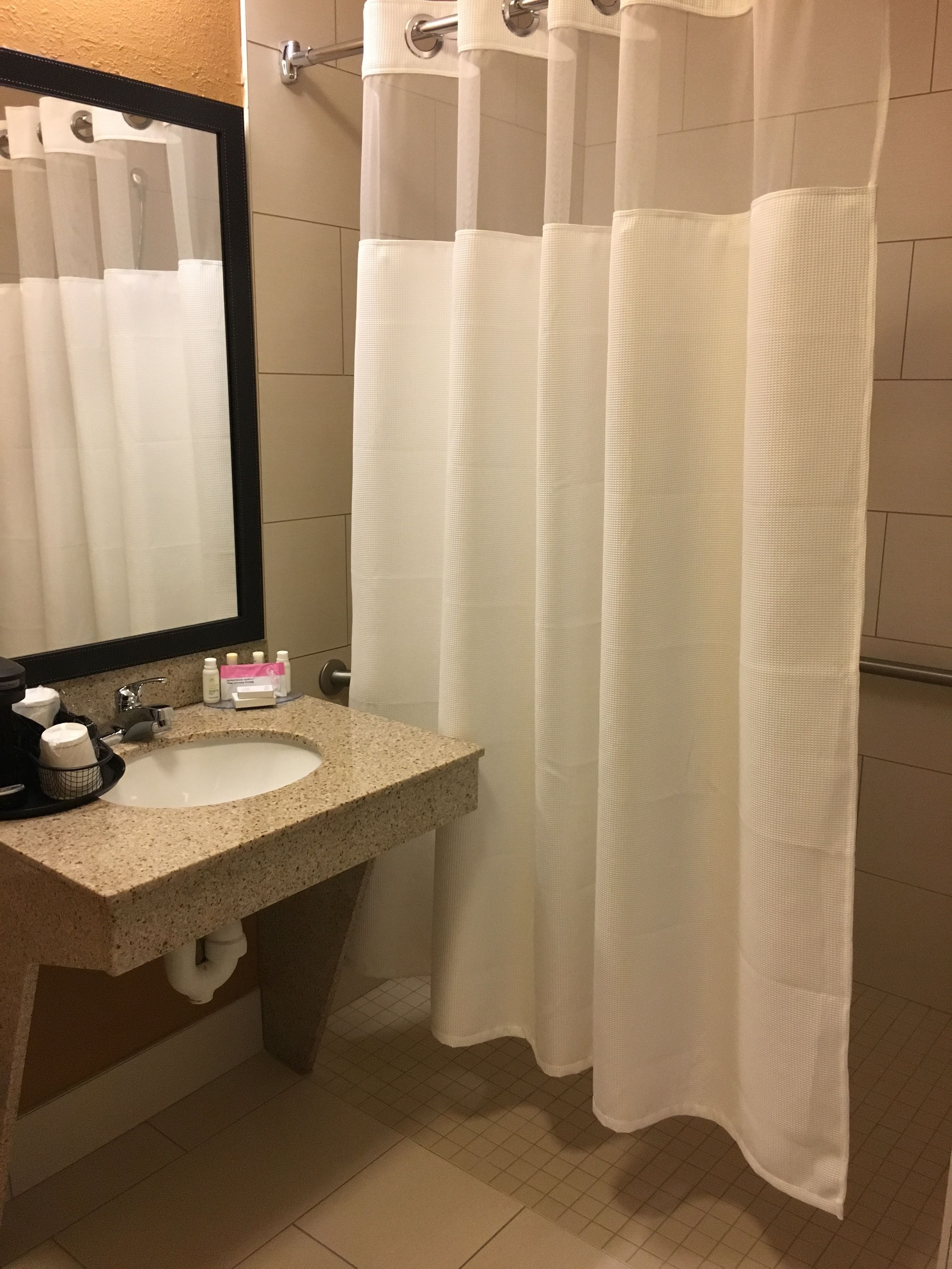 A bathroom with a sink, mirror, and shower curtain.