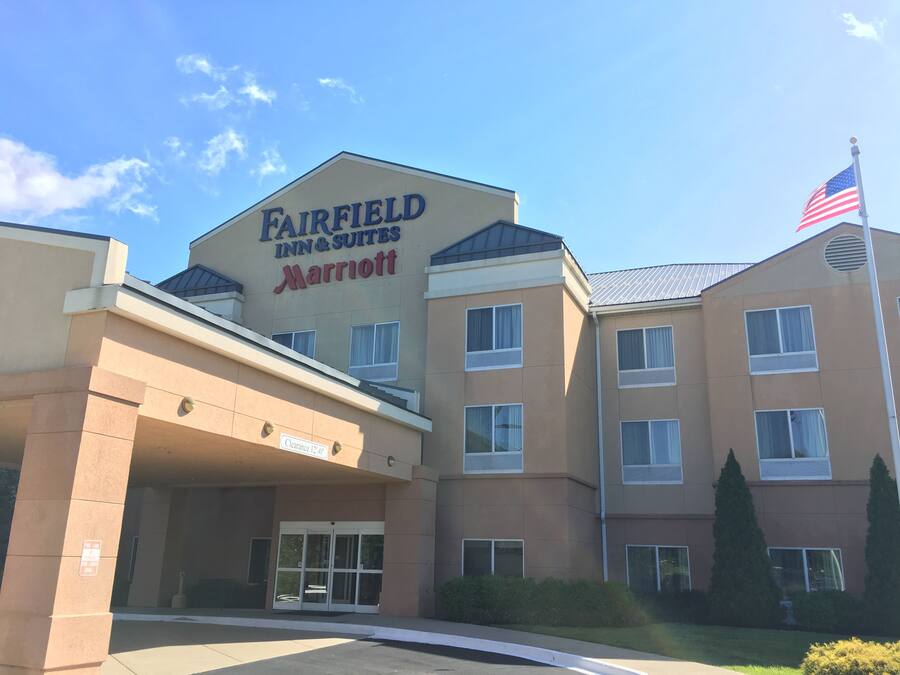 A Fairfield Inn & Suites Marriott hotel with a clear entrance, a flag, and a sign indicating a clearance of 12 feet.