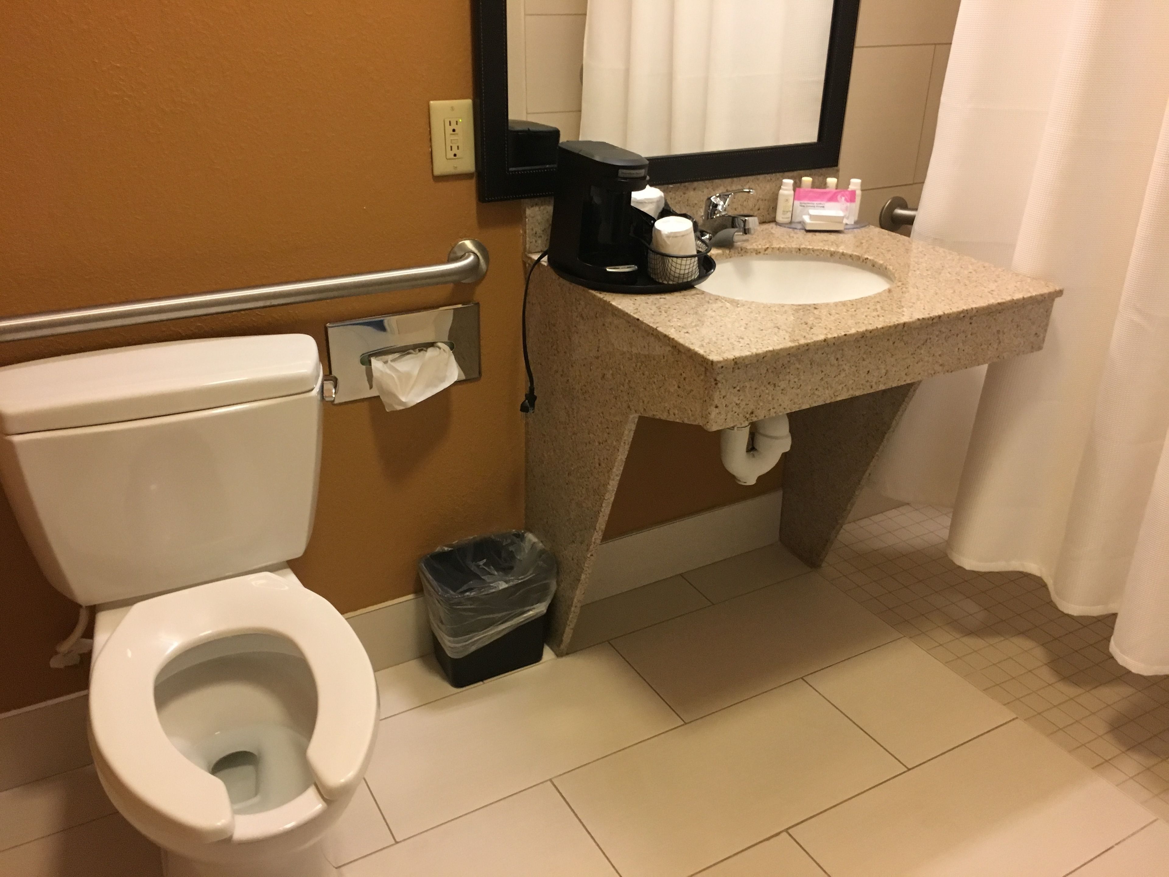 Un ba ño de hotel estándar con inodoro, lavamanos y secador de manos.