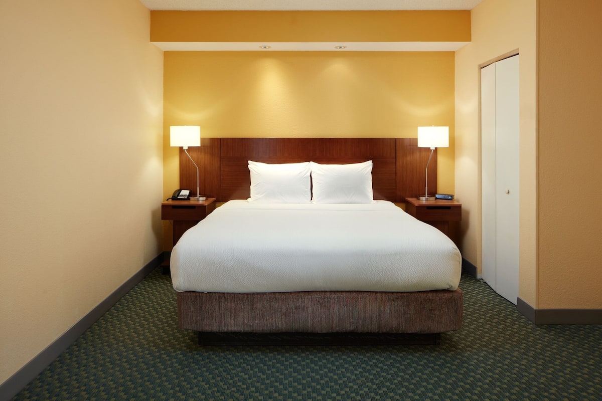 A hotel room with a large bed, two bedside tables with lamps, and a door.