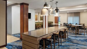 A hotel lobby with a long reception desk, multiple seating areas, and pendant lighting. - Fairfield Inn & Suites by Marriott Frankfort (Frankfort)