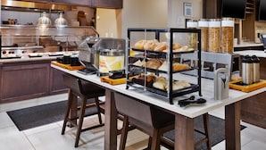 Montaje de un bufé de desayuno con diversas opciones de comida y una estación de café.
