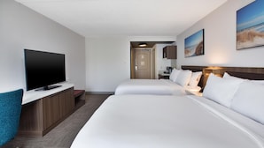 Habitación de hotel con dos camas, televisión, escritorio y kitchenette.