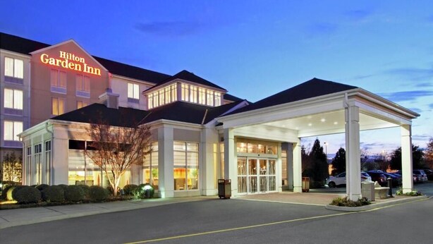 Un Hilton Garden Inn con una entrada bien iluminada y un estacionamiento techado.