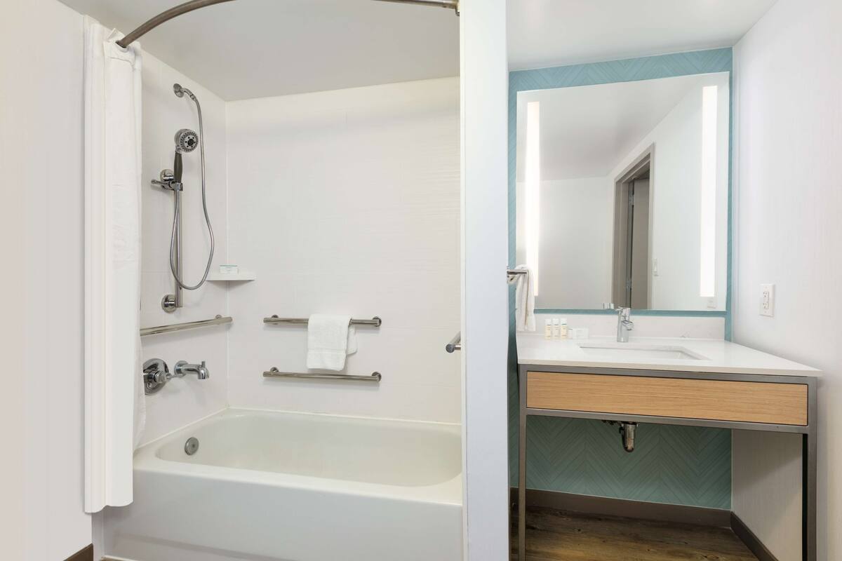 A bathroom with a bathtub, shower, and sink with a mirror.