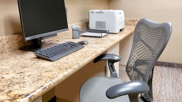 A workspace with a desktop computer, keyboard, mouse, and printer on a granite countertop.
