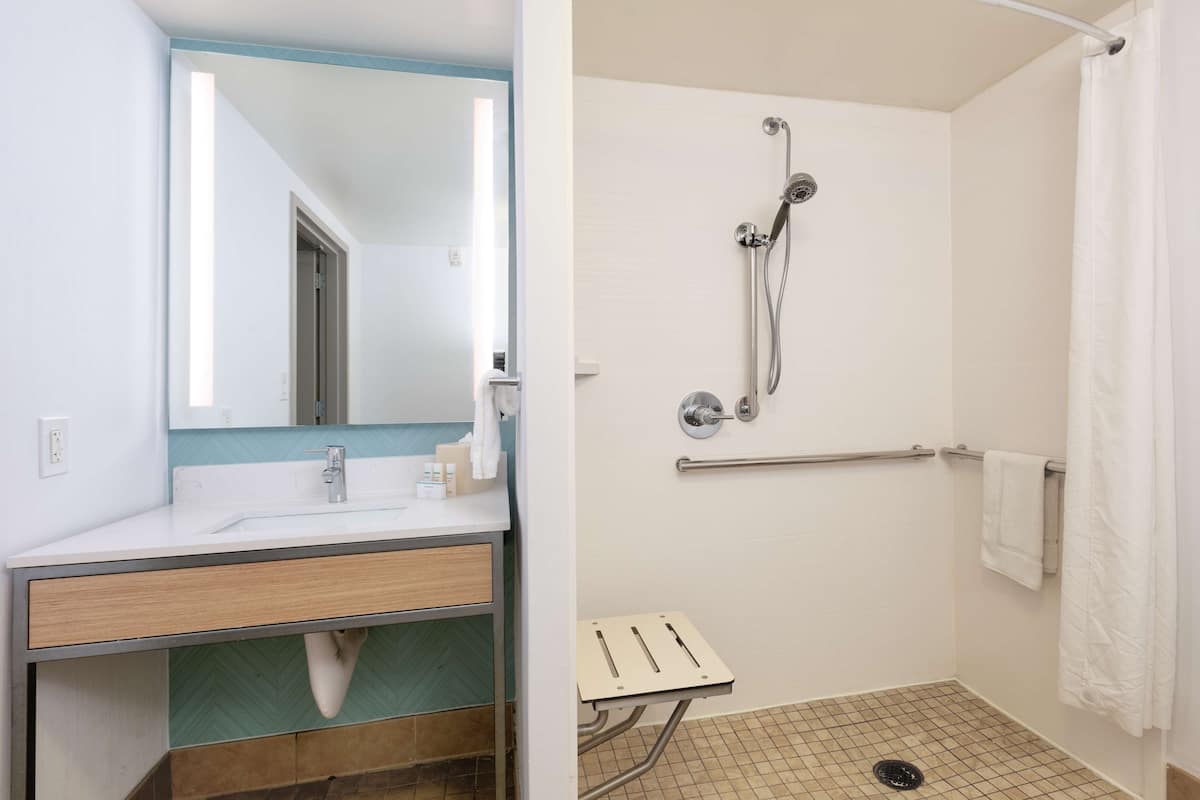 A bathroom with a sink, mirror, and shower.