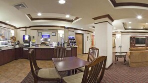 A hotel lobby with a central bar area, a dining table with chairs, and a seating area with a sofa. - Holiday Inn Express Hotel & Suites Cleveland by IHG (Cleveland)