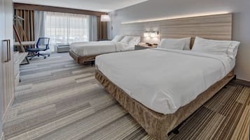 A hotel room with two beds, a desk, and a chair.