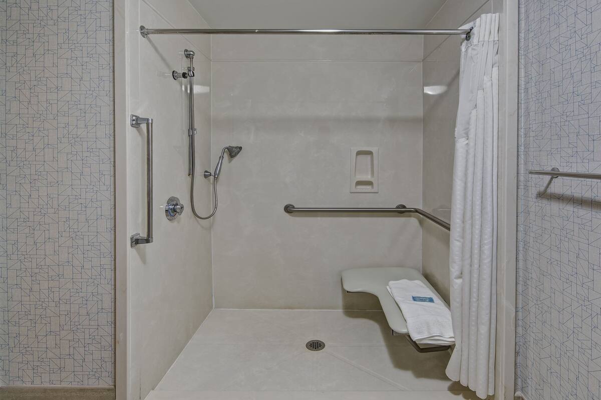 A small, enclosed shower area with a grab bar, a towel rack, and a showerhead.