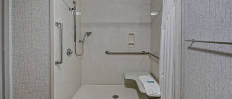 A small, enclosed shower area with a grab bar, a towel rack, and a showerhead.