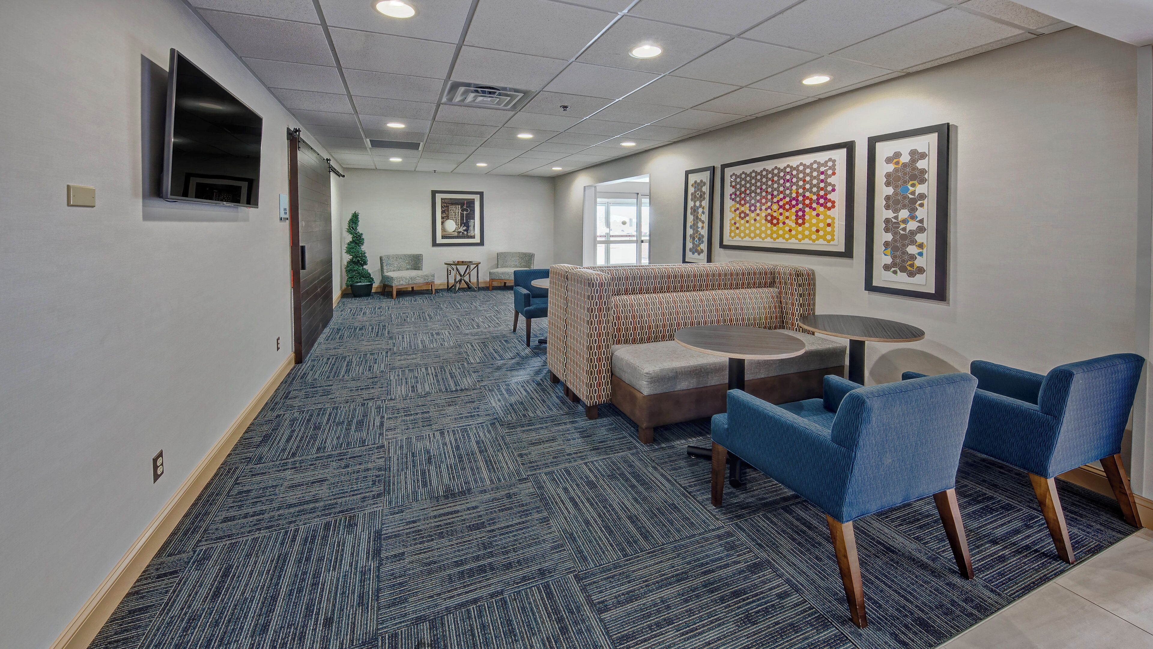 A hotel lobby with a patterned carpet, seating area with sofas and chairs, and artwork on the walls.