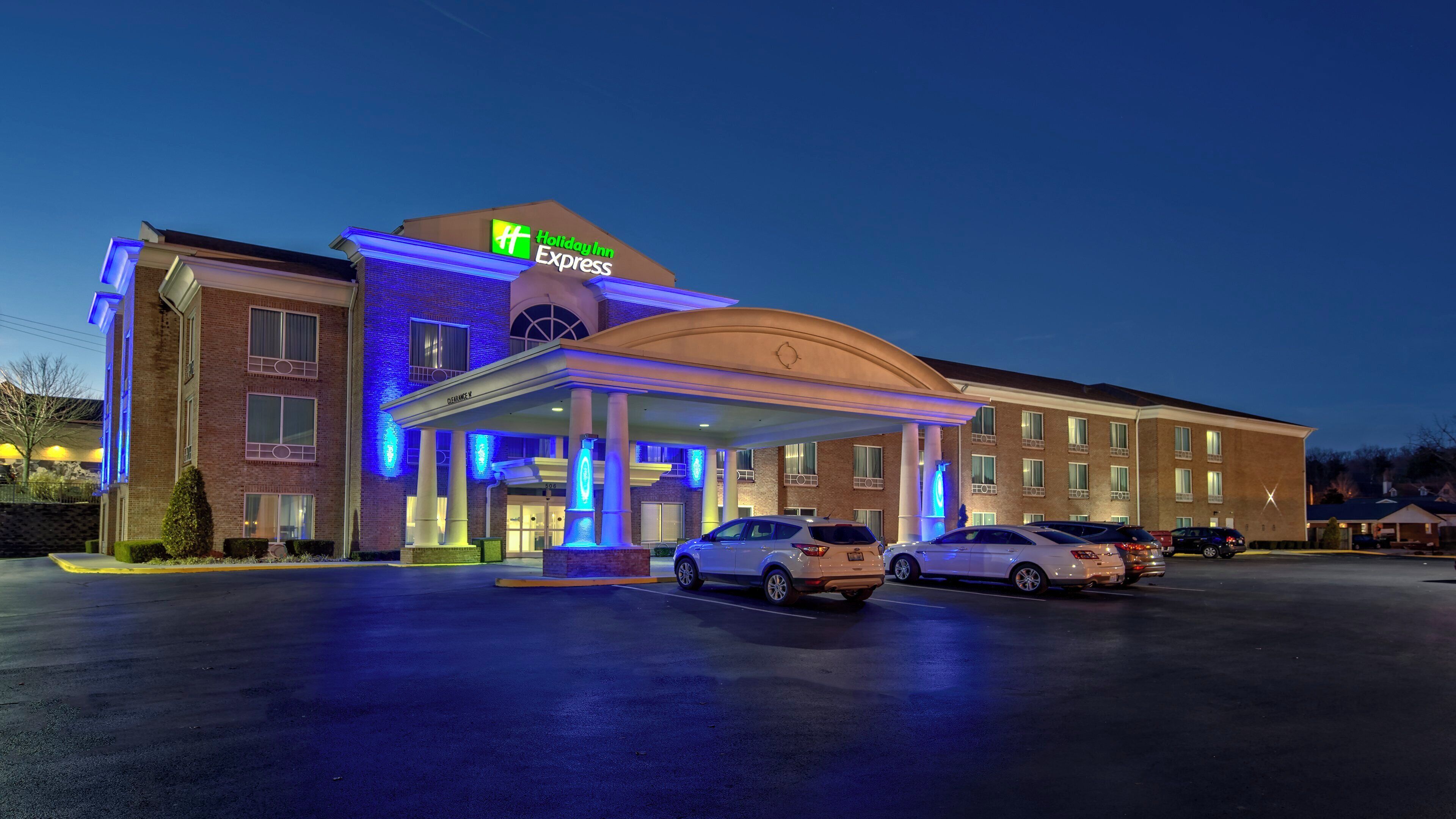 Ein Holiday Inn Express Hotel mit überdachter Zufahrt und mehreren parkenden Autos vor dem Haus.